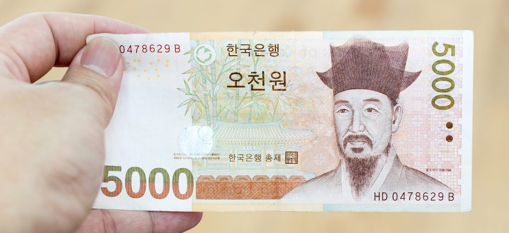 Business man hold south korea banknote 5000 korean won on wood background