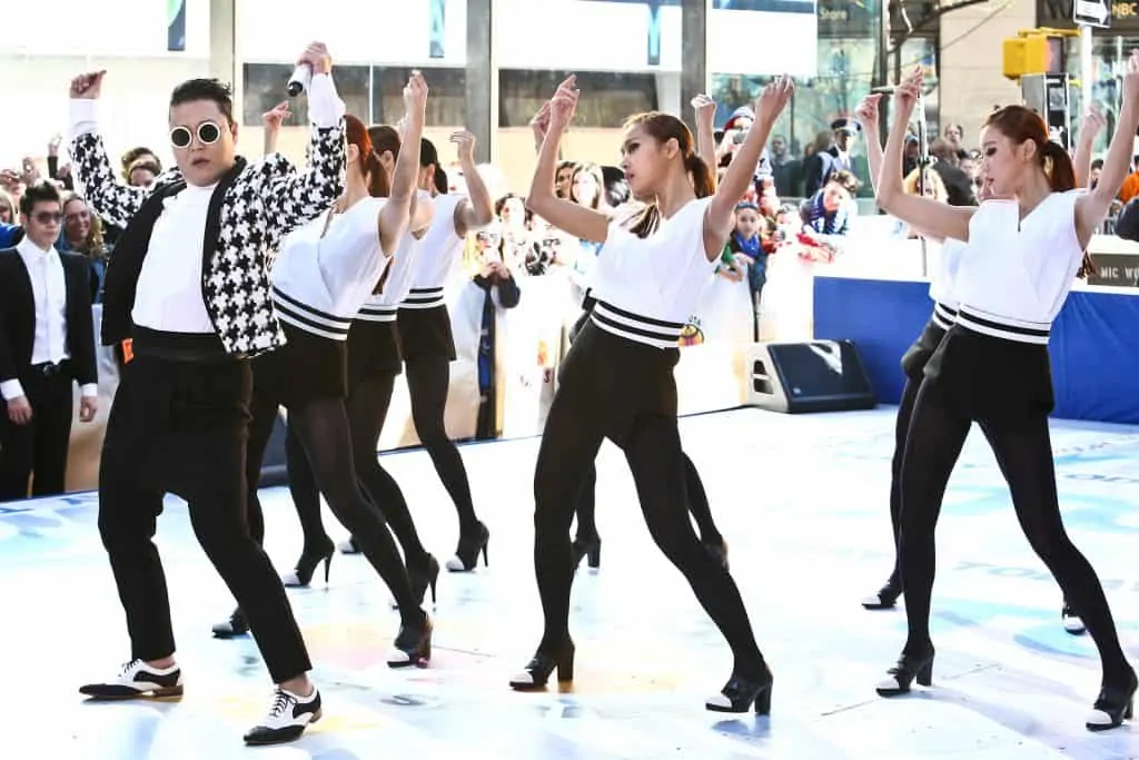 Psy and other females dancers wearing black and white with their arms up