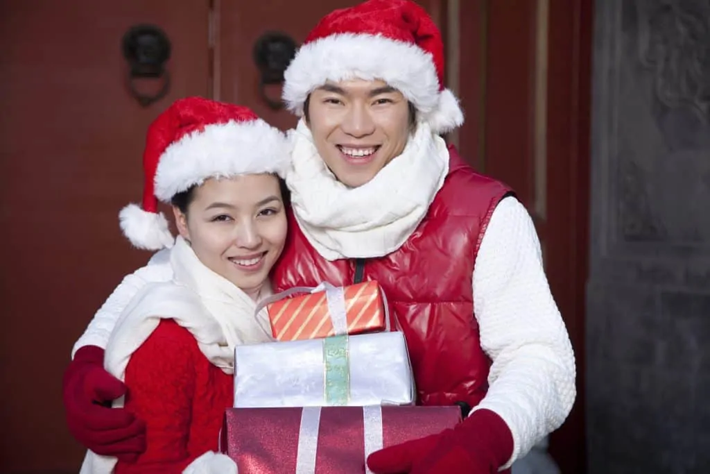 South Korea Facts: Man and woman wearing santa hats and festive clothes holding presents