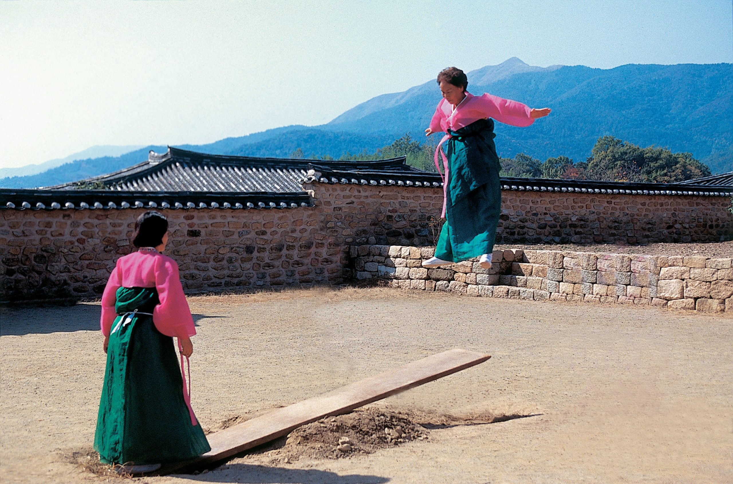 Two women wearing hanbok doing 널뛰기