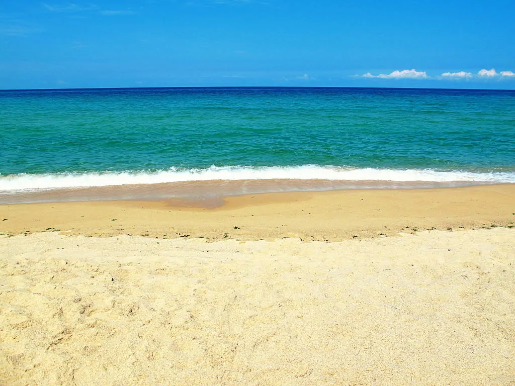 Picture of a beach with clear waters, brown sands, and clear skies
