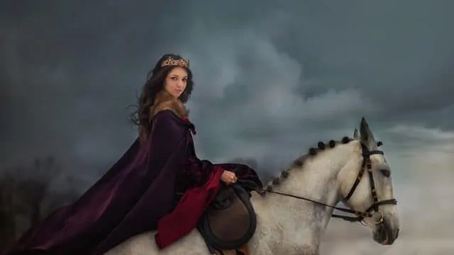Woman in a red cape and crown riding a white horse