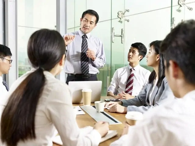 Asian Business Manager Talking To Team During Meeting